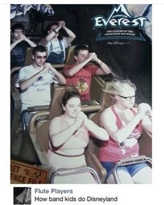 several people sitting on roller coasters at an amusement park in front of a sign