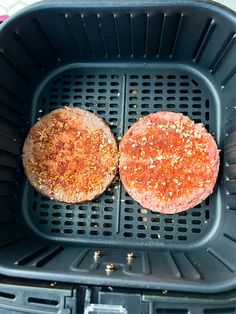 two hamburger patties sitting on top of an air fryer basket, ready to be cooked