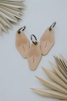 two wooden earrings sitting on top of palm leaves next to some scissors and other items