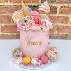 there is a pink cake with lots of cupcakes on it and an ice cream cone