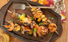 grilled shrimp and pineapple skewers on a plate with a glass of lemonade