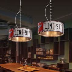 two light fixtures hanging from the ceiling in a room with wooden tables and shelves on both sides