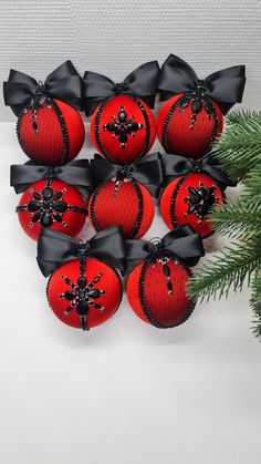 twelve red and black christmas baubles with bows on the top, surrounded by pine branches