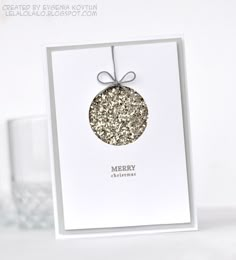 a white card with a christmas ornament hanging from it