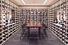 the wine cellar is full of many bottles and glasses on shelves, along with two dining tables