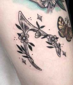 a woman's thigh with tattoos on it and butterflies flying over the top of her leg