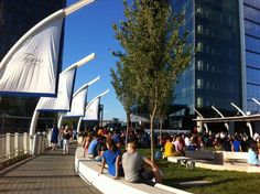 many people are sitting on benches in front of tall buildings