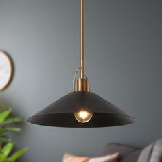 a black and gold pendant light hanging from a ceiling in a living room with a clock on the wall