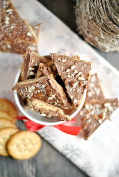 a bowl full of crackers sitting on top of a table next to some cookies