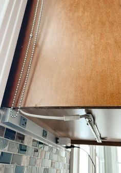 a kitchen light hanging from the side of a window over a counter top with tile backsplash