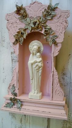 a pink shelf with a statue and flowers on it