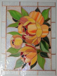 a stained glass flower with green leaves on a white tile back drop wall hanging in a bathroom