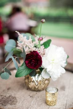 a vase filled with flowers sitting on top of a wooden table next to a candle