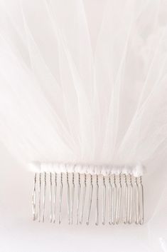 a close up of a hair comb on a white cloth covered surface with tulle