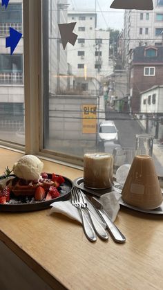 a plate with strawberries and ice cream on it next to a window