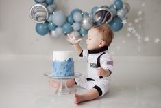 a baby boy sitting in front of a cake with blue frosting and stars on it