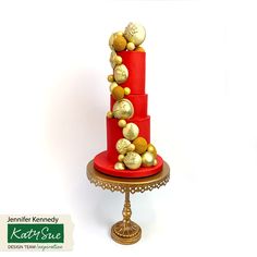 a three tiered red cake with gold balls on top