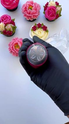 a gloved hand holding a cupcake with flowers on it