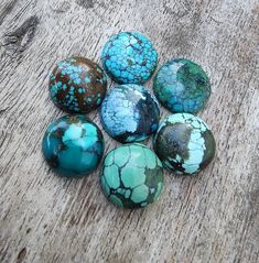 six turquoise and brown marbles sitting on top of a wooden table next to each other