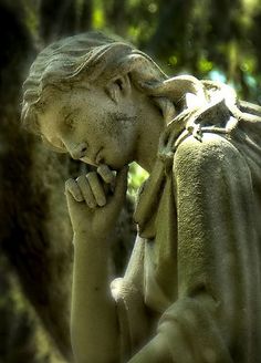 the statue is holding his head in his hands and looking down at something behind him