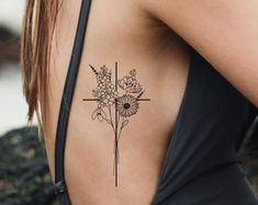 a woman with a cross and flowers tattoo on her upper back side ribcage