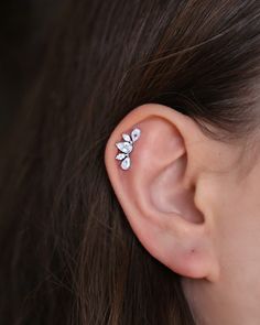 a close up of a person's ear with a flower shaped piercing on it