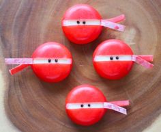 three red apples with tape on them sitting on top of a wooden table