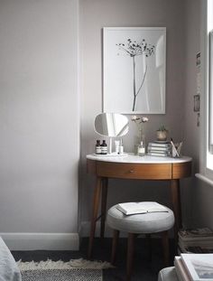 a bedroom with a vanity, mirror and stool next to a window in the corner