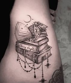 a woman's thigh with books and rosarys on her thighs, the tattoo design is