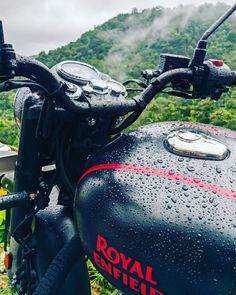 a motorcycle parked on the side of a road in front of a lush green hillside