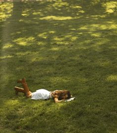 a woman laying in the grass with her legs spread out and head on her stomach