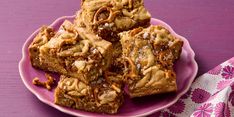 a pink plate topped with brownies covered in caramel