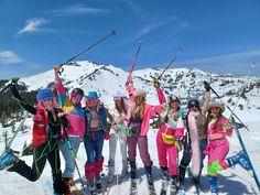 a group of people standing next to each other on top of a snow covered slope