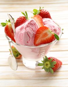 two scoops of ice cream with strawberries in the bowl