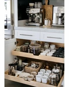 an open drawer in a kitchen filled with cups and saucers