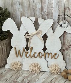 a wooden sign that says welcome with two rabbits