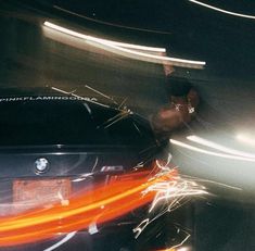 a car driving down a street at night with lights streaking through the cars windshield