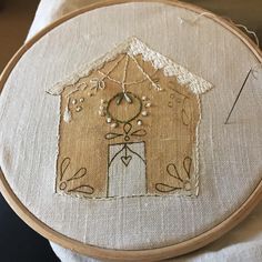 a close up of a embroidery on a piece of cloth with a house in the middle