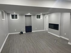 an empty room with hard wood floors and gray walls