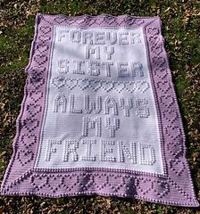 a purple crocheted blanket laying on top of the grass with words written in it