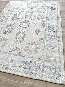 a white rug with blue and gray designs on the top is laying on a wooden floor