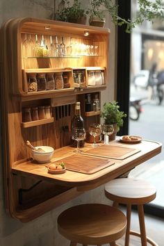 a wooden table topped with lots of bottles and glasses next to a wall mounted wine rack