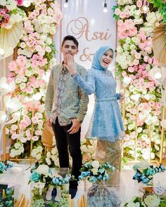 two people standing next to each other in front of a floral display with flowers on it