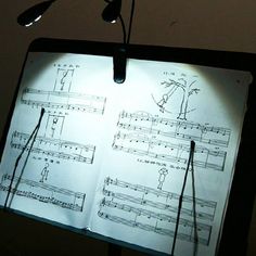 an open sheet of music is lit up in the dark with some strings attached to it