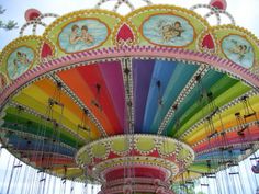 a brightly colored carousel with angels painted on it's sides and rainbow paint all over the top