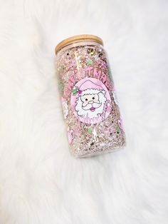 a pink santa clause glittered mason jar sitting on top of a white fur covered floor