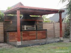 an outdoor bbq with grill built into the back wall and covered in wood planks