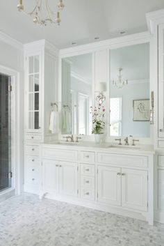 a white bathroom with double sinks and large mirrors on the wall, along with two walk in shower stalls