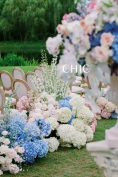 rows of chairs with flowers on them in the grass next to each other at a wedding