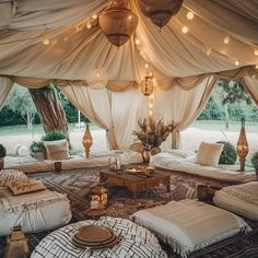 a living room filled with lots of pillows and lights hanging from the ceiling above it